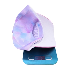 Tie-dye kids unicorn baseball cap weighing 73 grams on a digital scale in studio setting