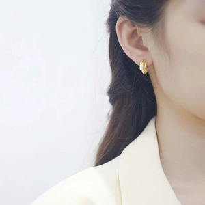 Minimalist double layered gold C-shape hoop earrings worn by a model in a side view