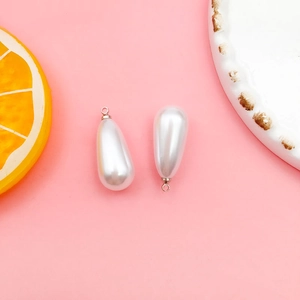 Detail of drop-shaped white pearl charms with silver metal rings for DIY jewelry making