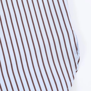 Détail de chemise en popeline rayée bleu et marron avec ourlet arrondi et couture