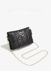 Detail of black quilted crossbody bag with golden heart buckle and chain strap