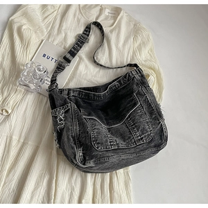 Détail du sac bandoulière en jean noir délavé avec bords effilochés et poches à rabat