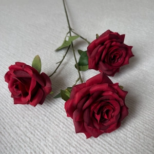 Close-up of artificial red rose bouquet with three blooming silk flower heads and leaves