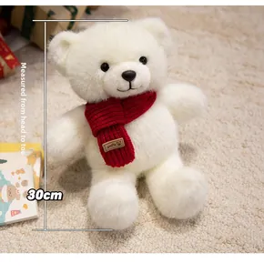 Close-up of a 30cm white plush teddy bear with a red knitted scarf and smile leather tag