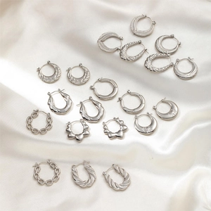 Variety of minimalist silver stainless steel earrings on a luxurious white silk background