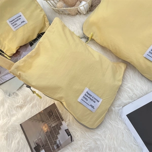 Detail view of yellow waterproof nylon travel storage bag with woven label on soft carpet