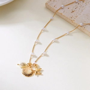 Gold ocean themed necklace with pearls, shell and starfish pendants on stone plate