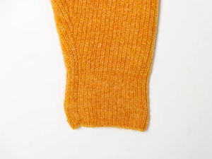Detail of solid mustard yellow knit sweater showing ribbed cuffs and soft fabric texture