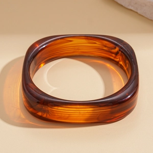 Macro shot of geometric resin bangle with amber marble texture and glossy finish