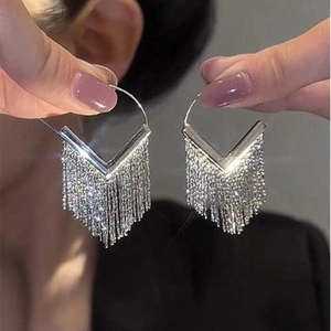 Close-up of silver tassel earrings with V-shaped hooks and shimmering diamond-like fringe