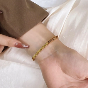Elegant gold fish scale chain bracelet worn with stylish suit and silk dress