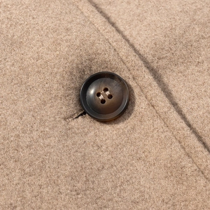 Detailed macro view of high-quality wool coat fabric texture and brown resin buttons