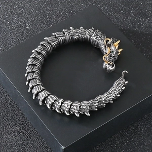 Close-up of dragon bracelet with golden horns, green eyes, and silver scale texture