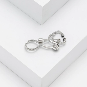 Detailed view of a silver stethoscope brooch featuring a sparkling small diamond accent