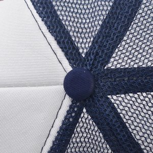 Detail of the navy top button and white twill fabric with breathable mesh on a baseball cap