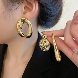 Detailed view of polished gold abstract earrings with irregular and hollow designs