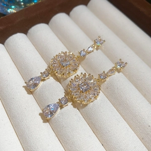 Makroaufnahme von Gold-Ohrringen mit hängenden Zirkonia-Wassertropfen in einem Tablett