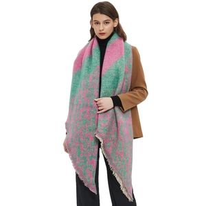 Pink and green plaid scarf with fringe tassels worn by a model on white background