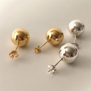 Macro shot of polished gold and silver spherical stud earrings with butterfly backings