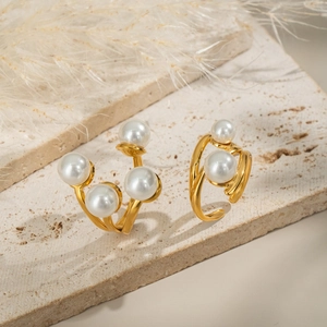 Elegant geometric gold pearl earrings set displayed on a minimalist marble stone surface