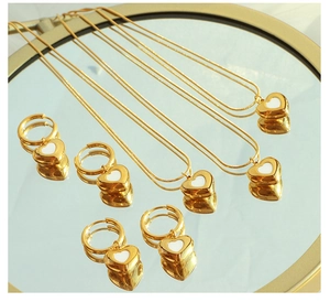 Detailed view of gold heart necklace and earrings set on a reflective mirror surface