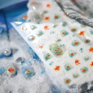 Macro detail of goldfish nail art stickers with orange fish and blue water grass patterns