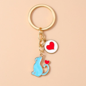 Detail of blue cat charm and red heart enamel pendant on golden keychain ring