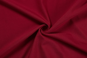 Detail of dark red textile fabric showing soft spiral texture and metallic sheen