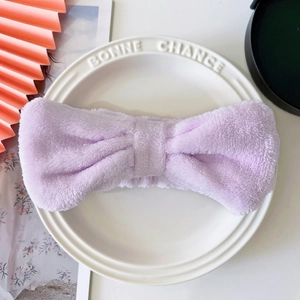 Detailed view of purple coral fleece headband with bow on decorative ceramic plate