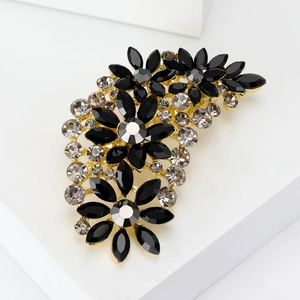 Detailed close-up of a floral alloy brooch featuring black and clear crystals on a gold base