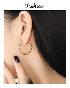 Close-up of golden hoop earrings with high-polish finish on female model ear