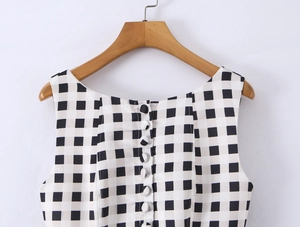Detail of black and white plaid sleeveless top with white buttons on the back on wood hanger