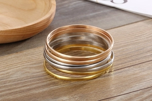 Detailed view of stacked gold, silver and rose gold brushed titanium steel bracelets