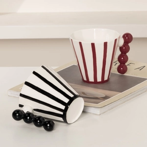 Minimalist ceramic mugs with vintage stripes and creative spherical handles on white surface