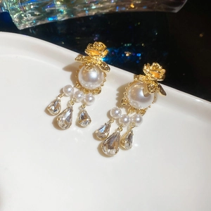 Detailed macro view of vintage gold flower earrings with hanging pearl and crystal tassels