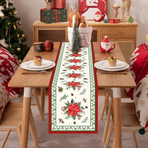 Christmas table runner with red poinsettia and holly leaves on festive dining setting