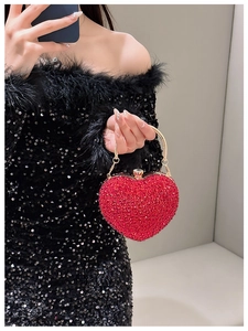 Model holding a red heart-shaped rhinestone evening bag with gold metal handle