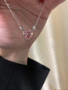 Close-up of a pink heart-shaped crystal pendant on a dainty silver clavicle chain