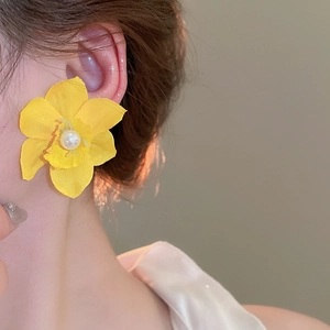 Detailed macro view of yellow silk fabric floral earring with elegant pearl center