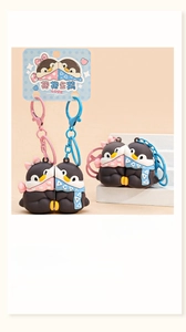 Close-up of cute 3D hugging penguin keychains in pink and blue with magnetic heart feature