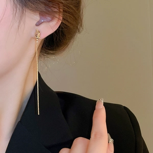 Vue détaillée d'un mannequin portant d'élégantes boucles d'oreilles nœud doré à franges