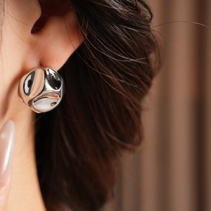 Close-up of polished silver geometric round earrings on model with sleek metallic finish