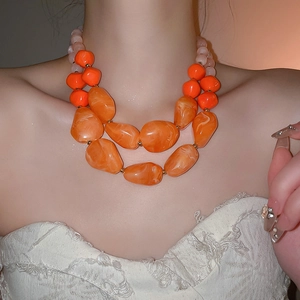 Close-up of double-layer chunky acrylic necklace with irregular orange and pink beads