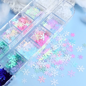 Macro shot of colorful 12-grid Christmas snowflake nail sequins in clear storage box