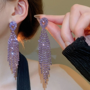 Close-up of purple teardrop tassel earrings with sparkling rhinestones on model