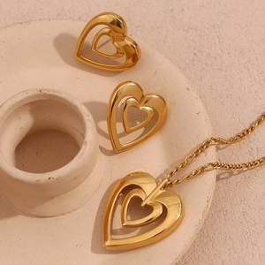Close-up of 18K gold plated heart necklace and earrings set on ceramic display