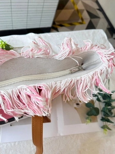 Detail der rosa-weißen Fransenquasten mit Reißverschluss an einer Canvas-Einkaufstasche