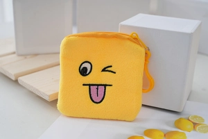Detail of yellow plush coin purse with wink emoji embroidery and matching plastic hook