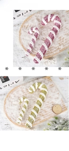 Close-up of pink and gold Christmas candy cane ornaments on a snowy wooden tray