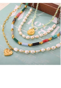Detail of layered handmade natural stone bead necklaces with pearls and heart pendant